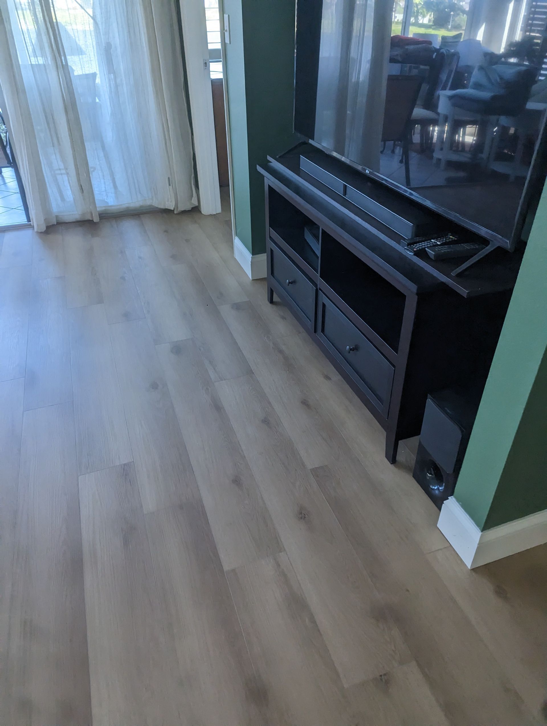 A living room with hardwood floors and a flat screen tv on a stand.