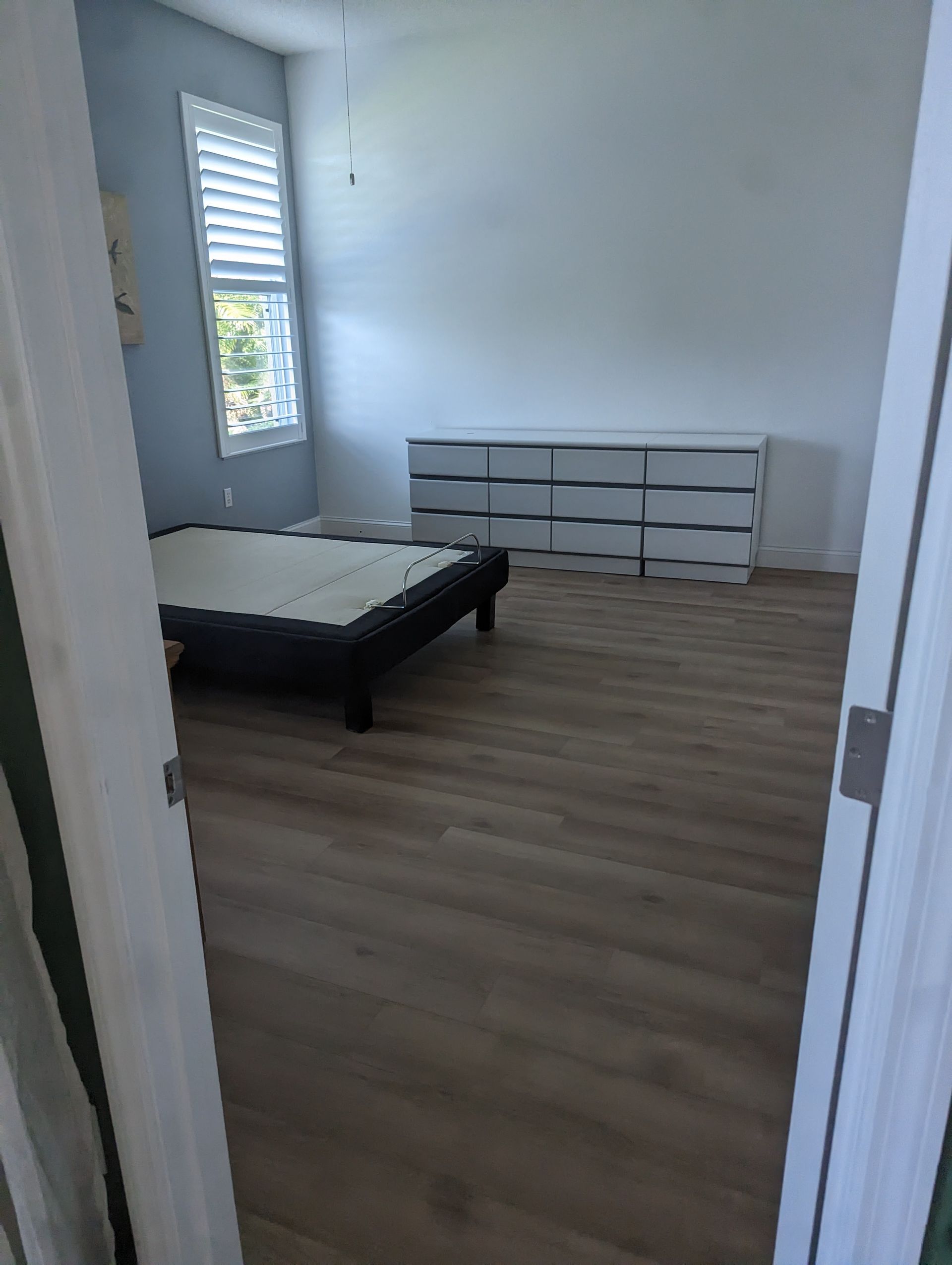 A bedroom with a bed , dresser , and window.