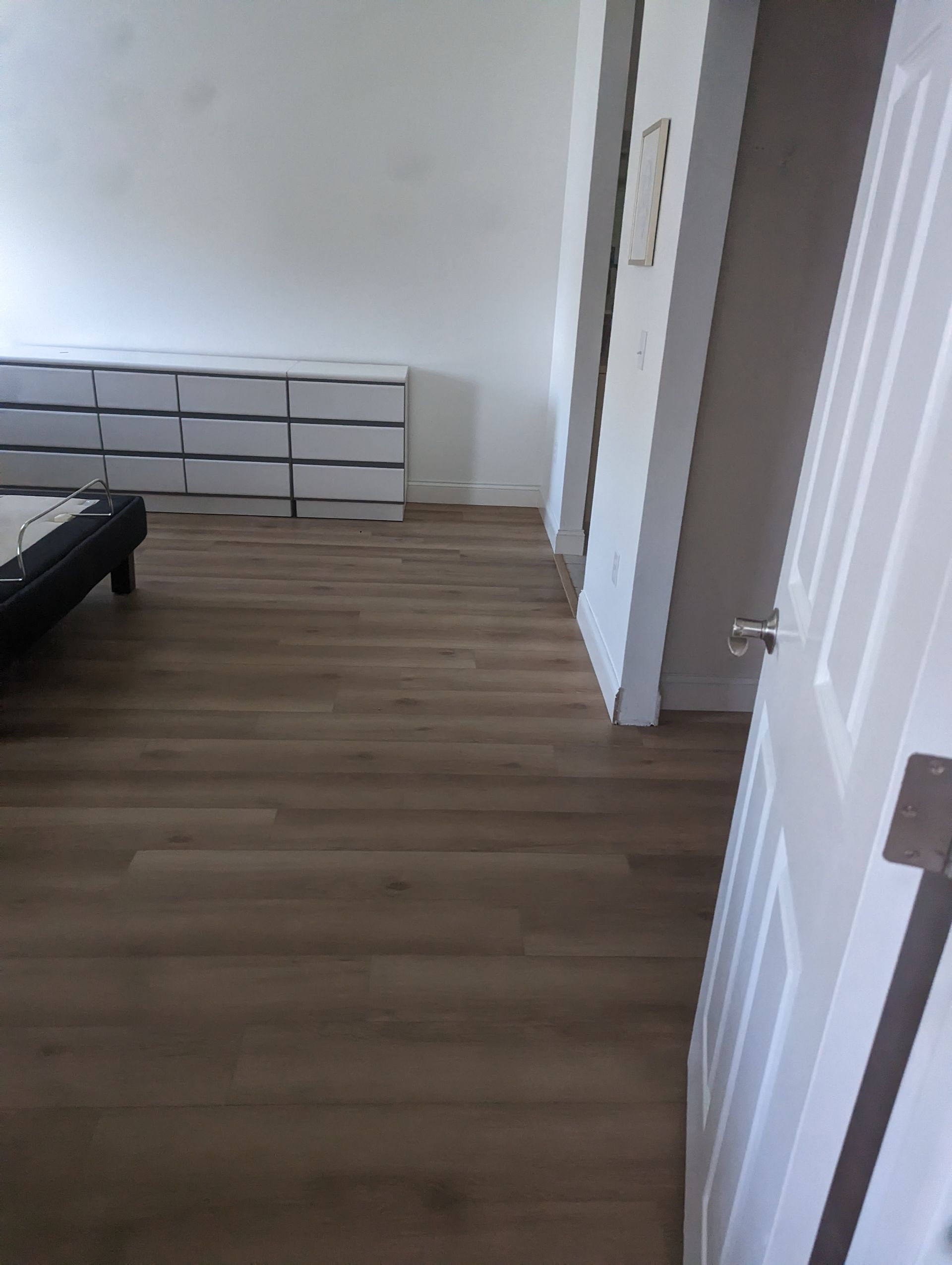 A bedroom with hardwood floors and a bed.