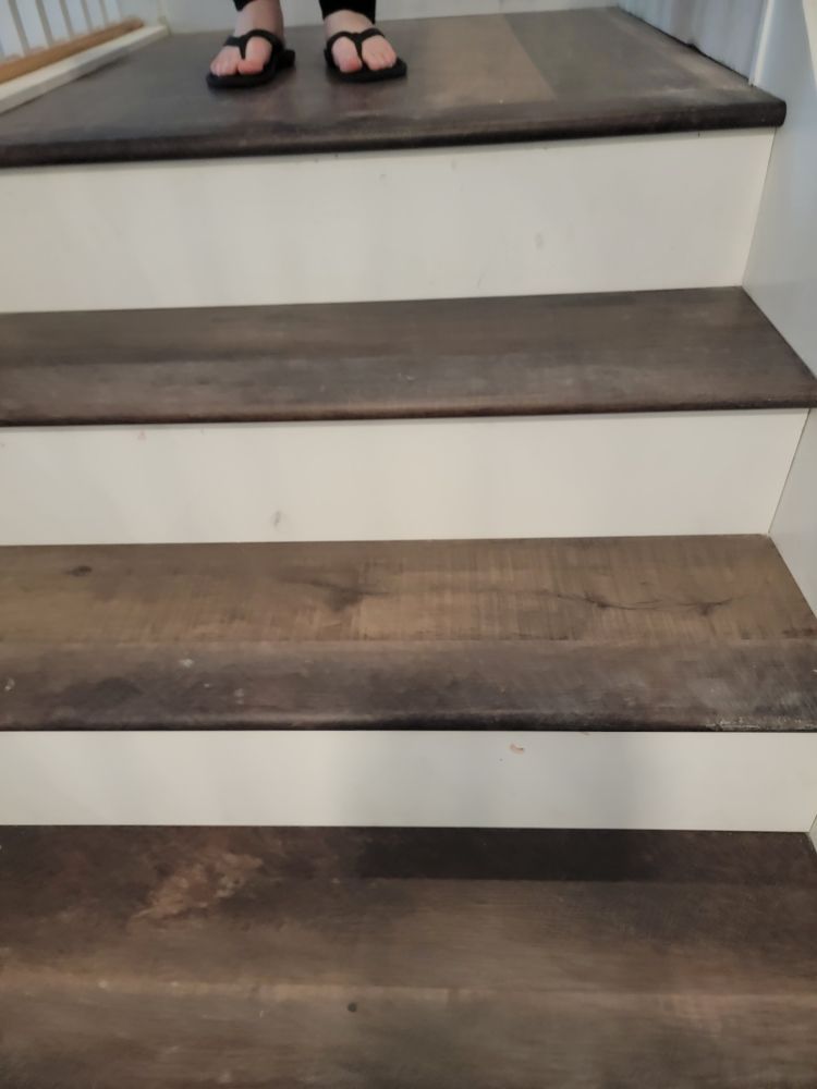 A person wearing flip flops is standing on a set of wooden stairs.