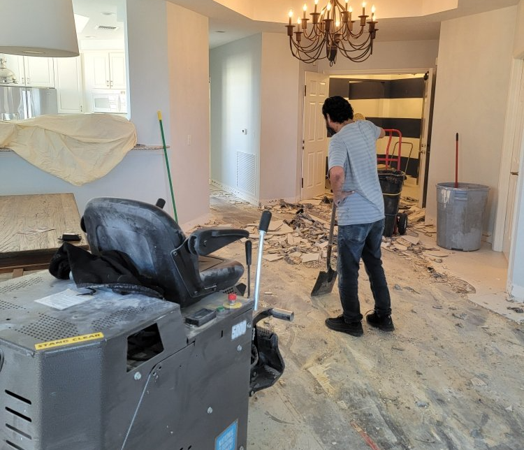 A man is standing in a room with a shovel in his hand.