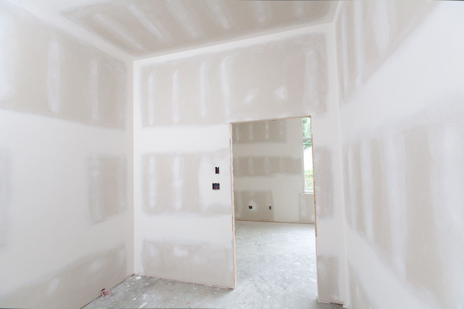 An empty room with drywall walls and a door.
