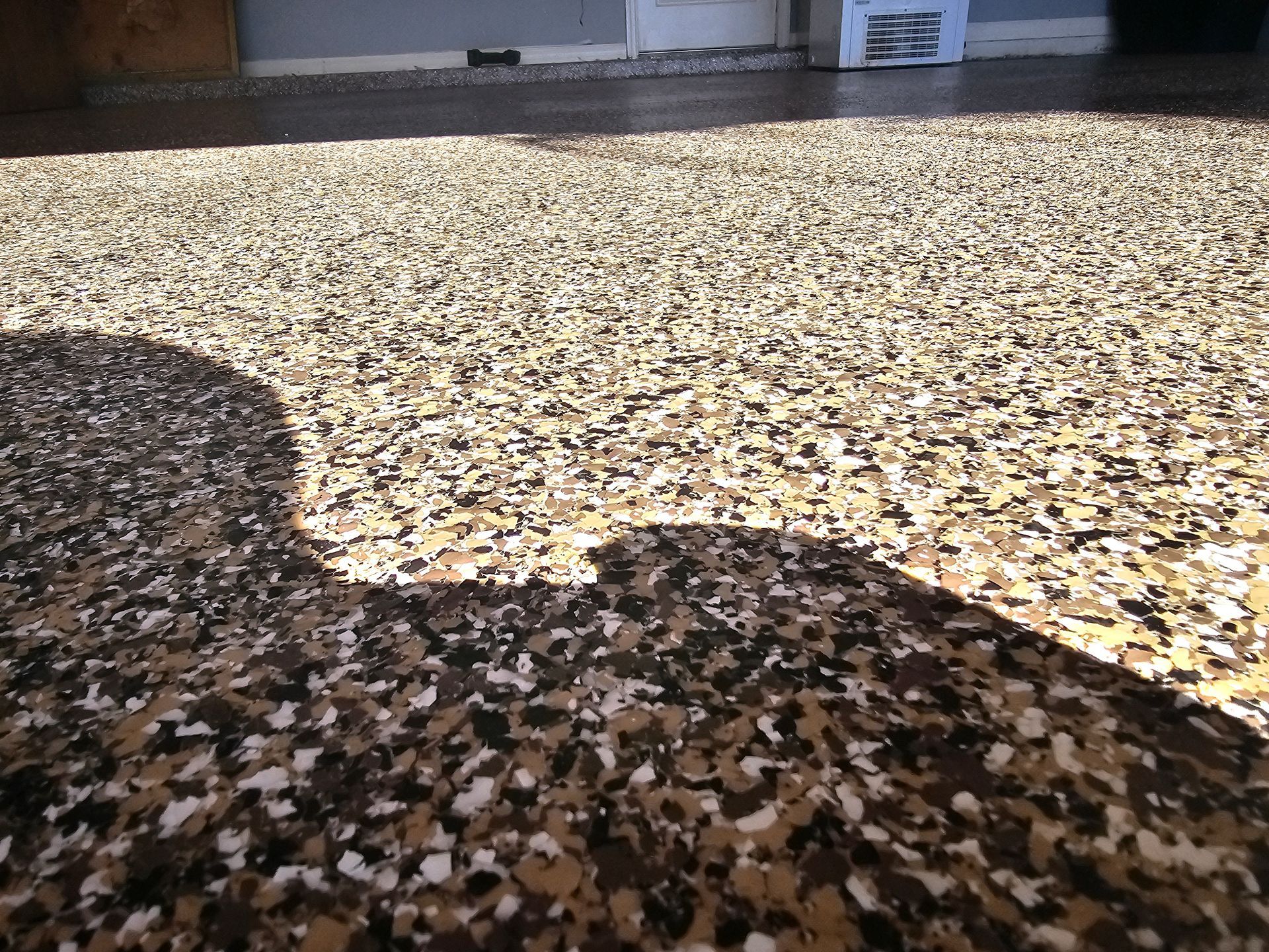 Open garage with shelves, tools, and a white door in the back. Gray floor and walls.