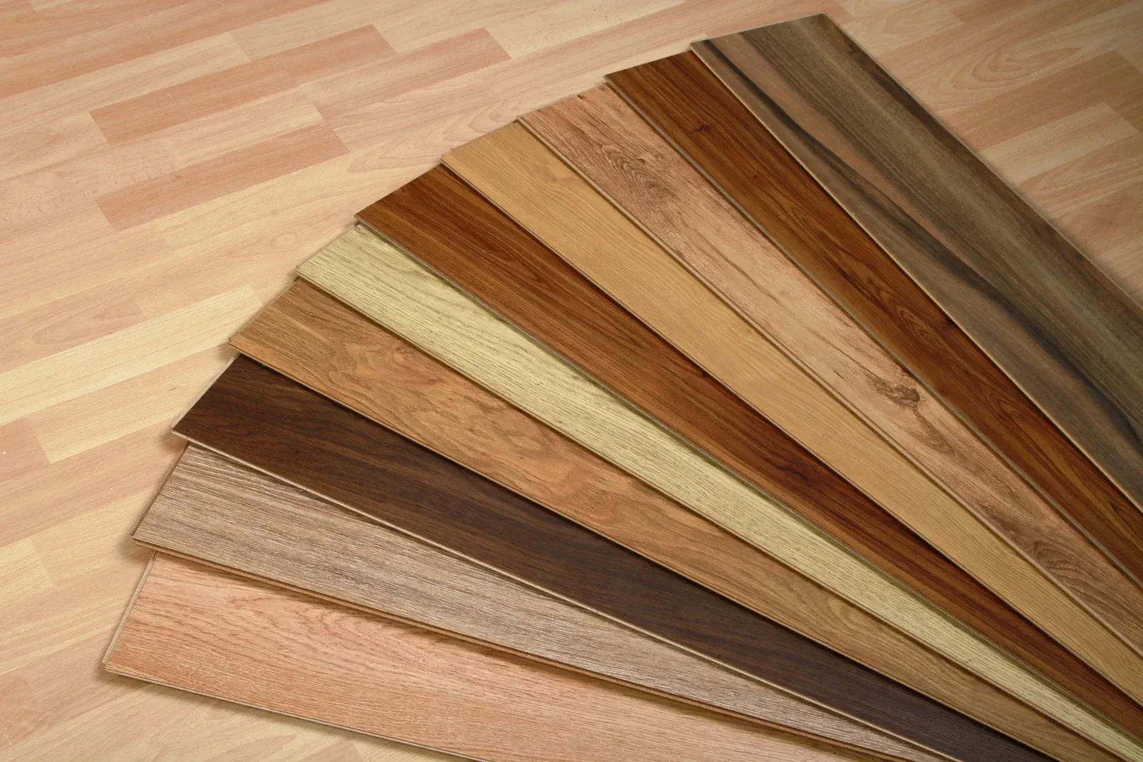 A fan of various hardwood flooring samples in shades of brown and tan, showcasing wood grain patterns.