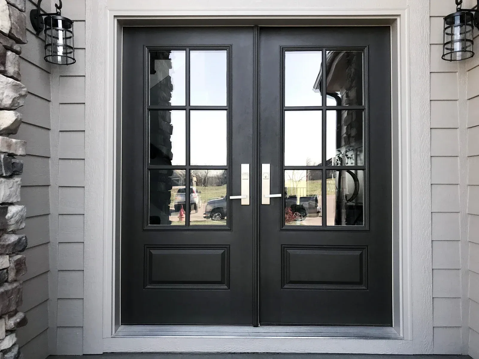 Double black front doors with glass panes and gold handles.
