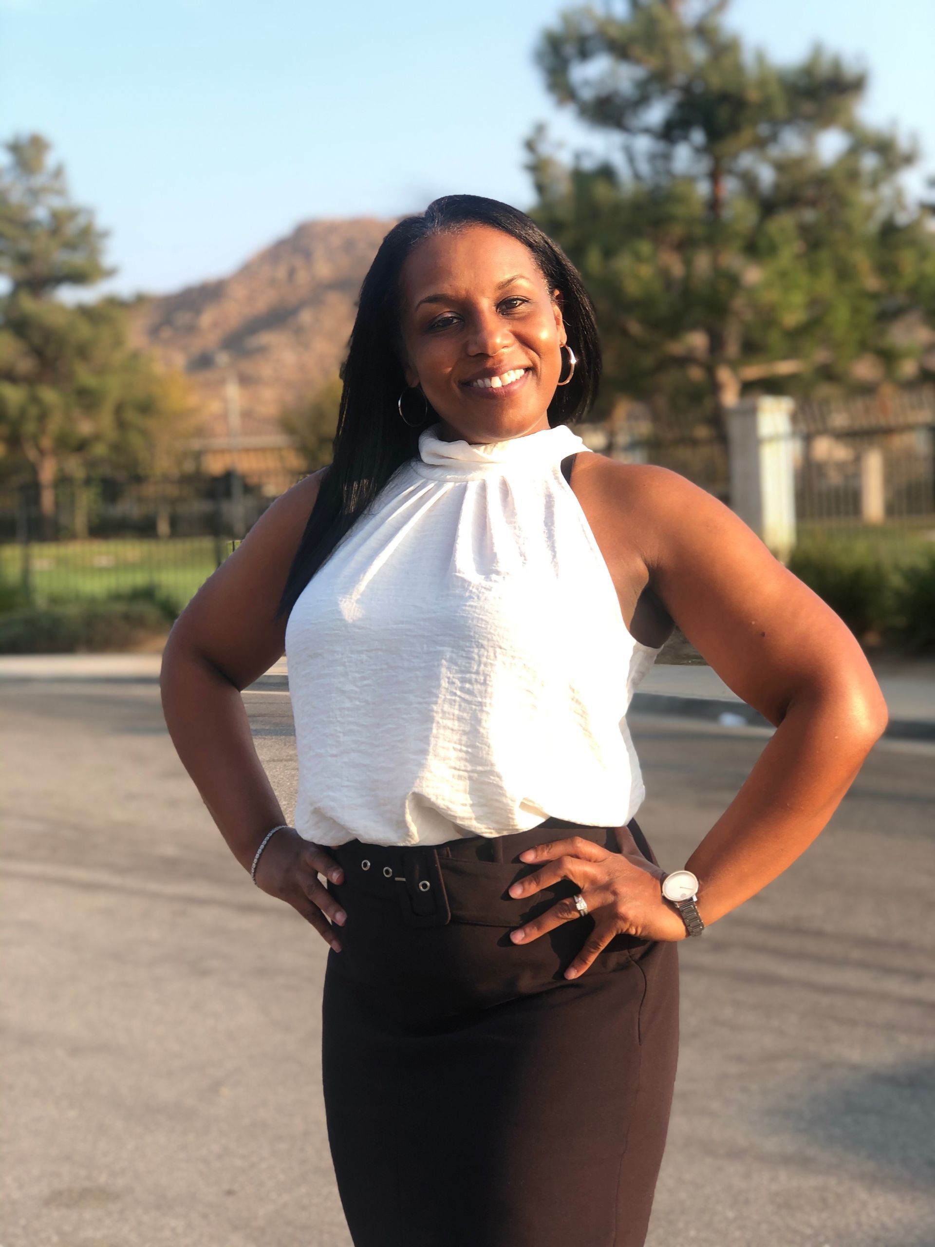 A woman in a white top and black skirt is posing for a picture.