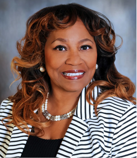 A woman wearing a black and white striped jacket is smiling
