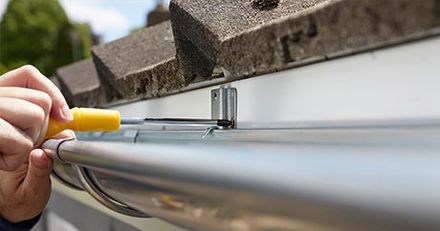 Illinois Gutter Services — Worker Holding Screw Driver in Gutter Installation in Lagrange, IL