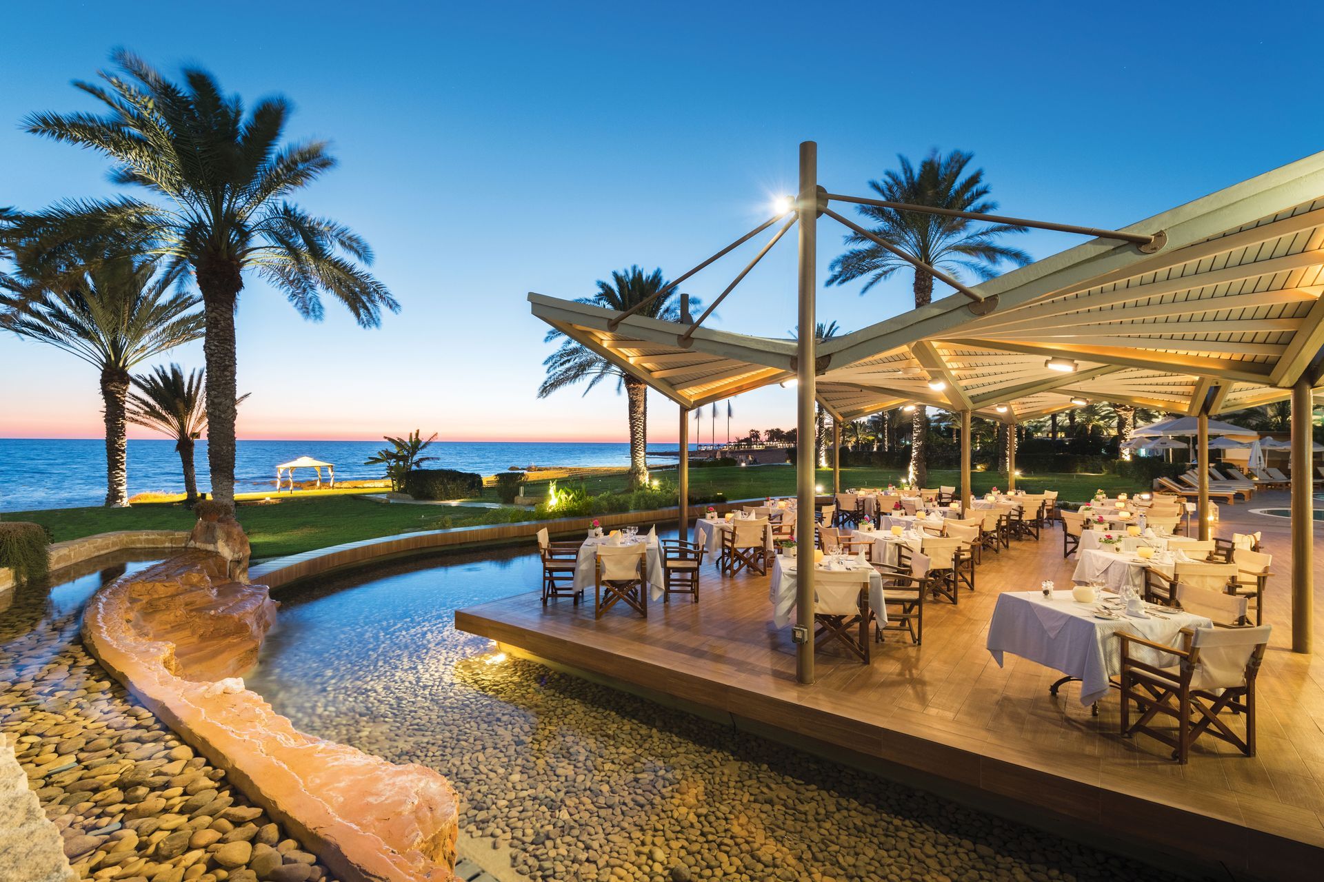 A restaurant with tables and chairs in front of the ocean