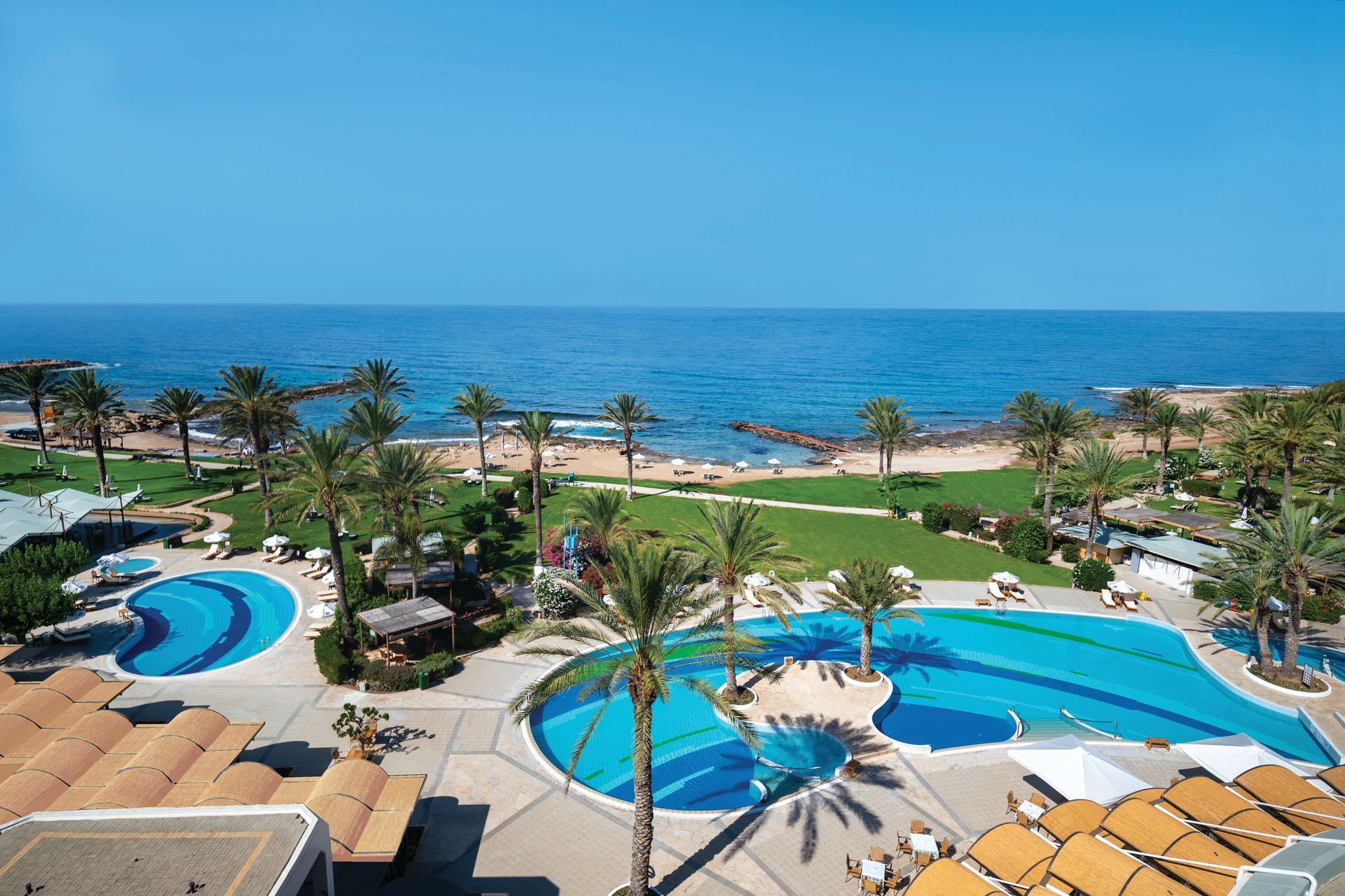 Constantinou Bros Hotels An aerial view of a resort with swimming pools and a beach.