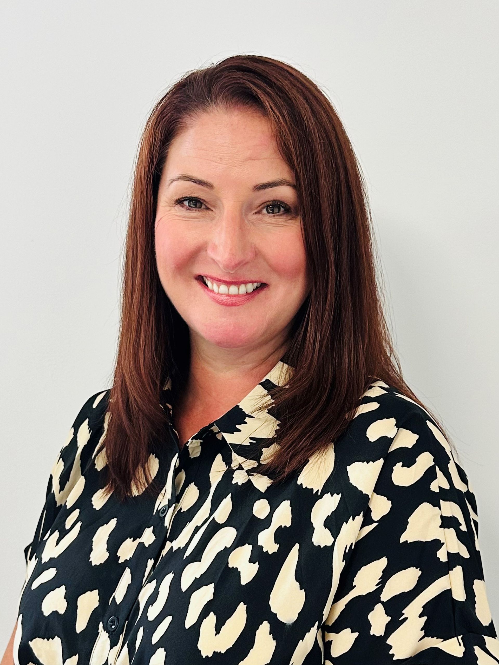 A woman wearing a leopard print shirt is smiling for the camera.