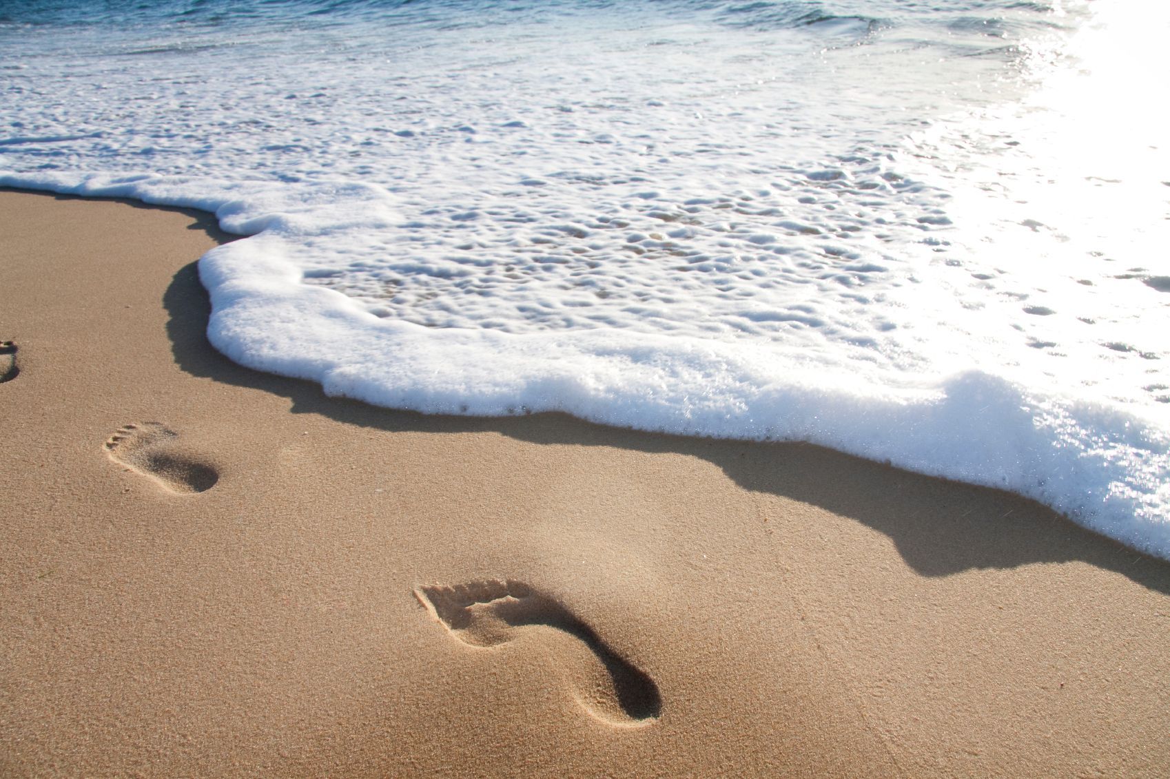 Family Holidays A family is sitting on the beach with their arms in the air.