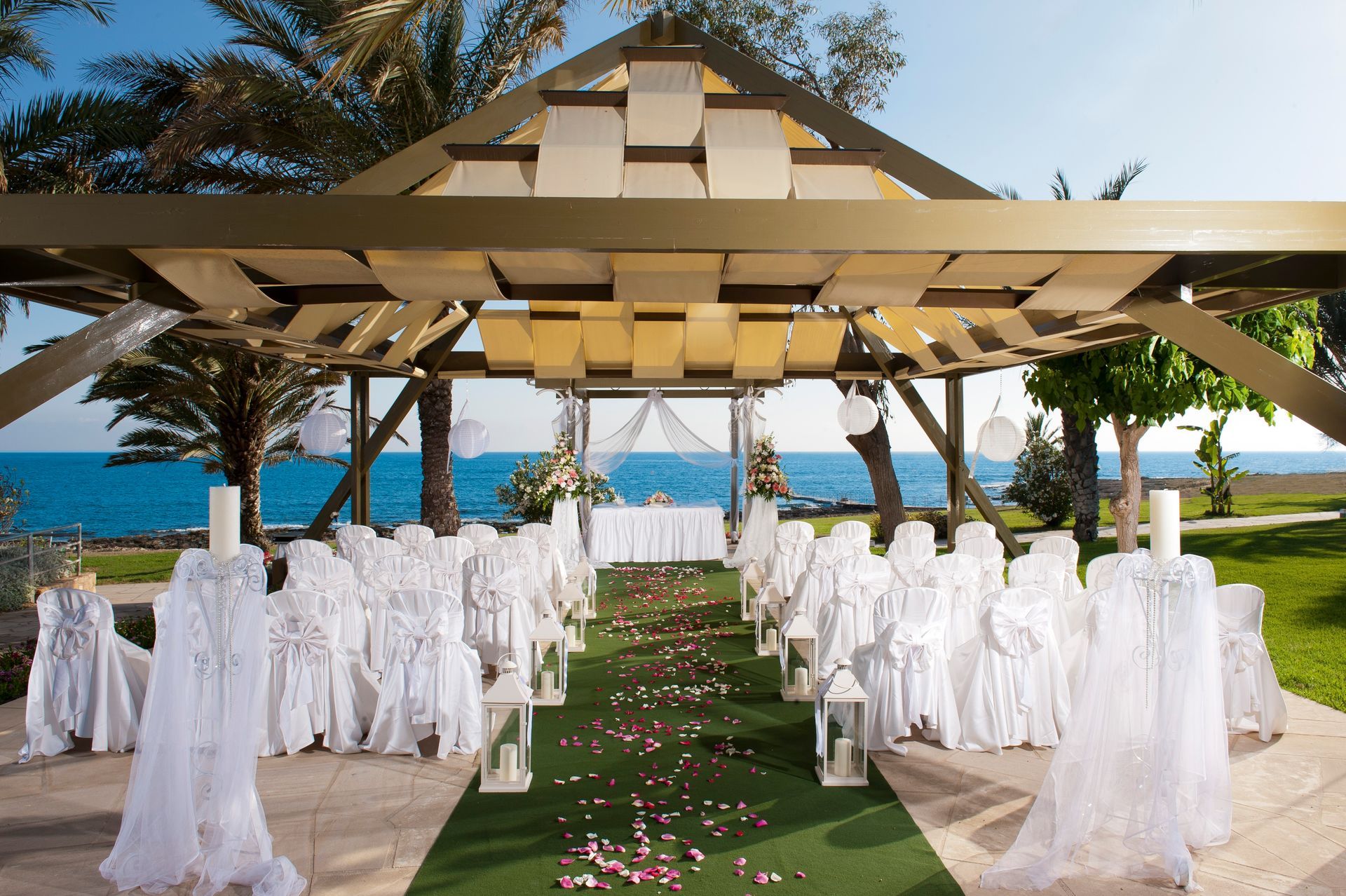 A wedding ceremony is taking place under a gazebo in front of the ocean.