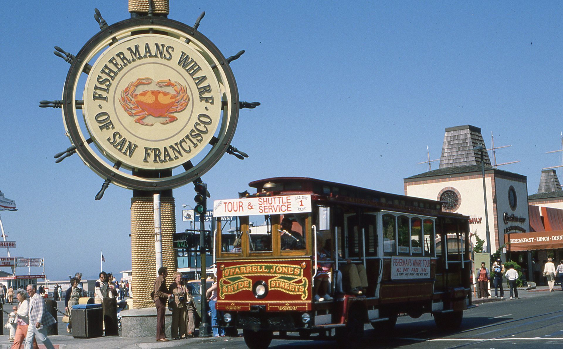 San Francisco Fisherman’s Wharf sign beside a red-and-green trolley bus on the waterfront