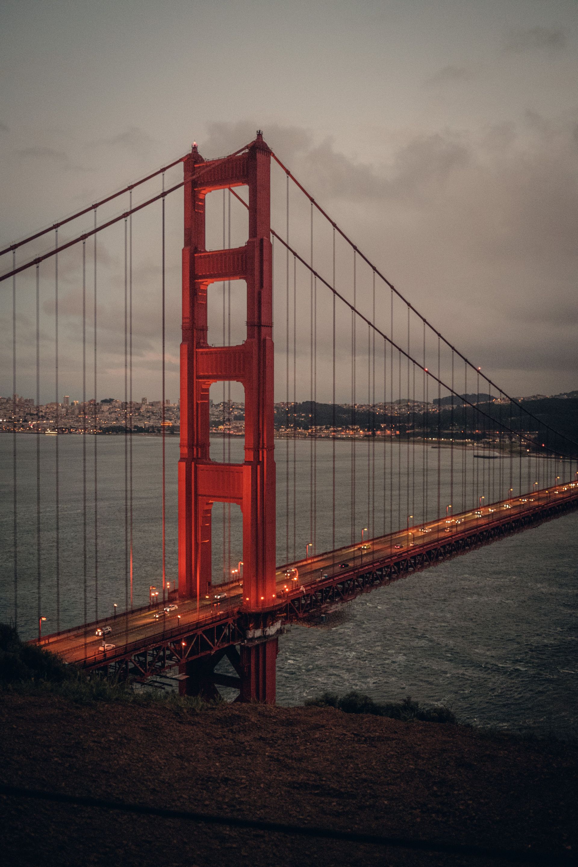 Golden Gate Bridge in red spanning a calm bay under a cloudy sky.