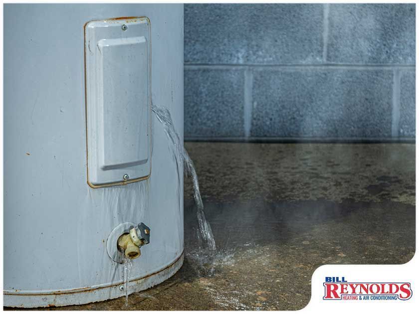 A leaking water heater in a basement, with water pouring out onto the concrete floor.