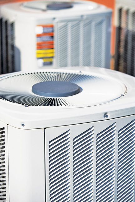 White air conditioning units in a close-up shot, with a fan on top and grilles on the sides.
