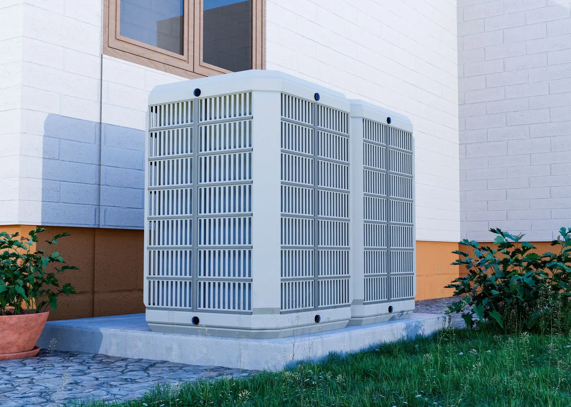 Two white air conditioning units outside a building with a window, beside green grass and a potted plant.