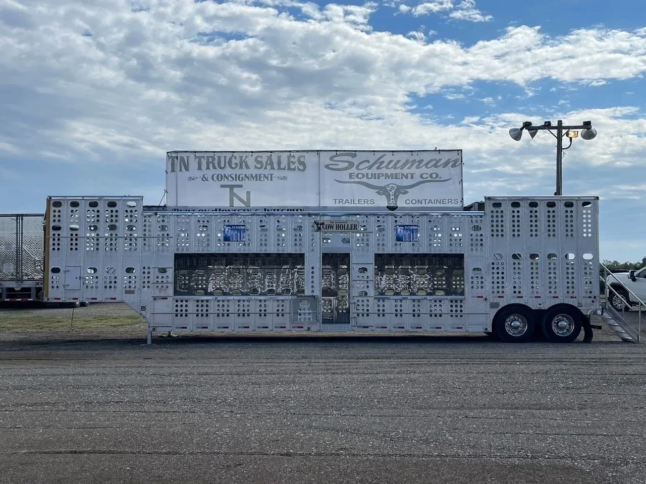 Trailer parked in a lot with “Jr Thomas Sales” signage and cloudy sky overhead