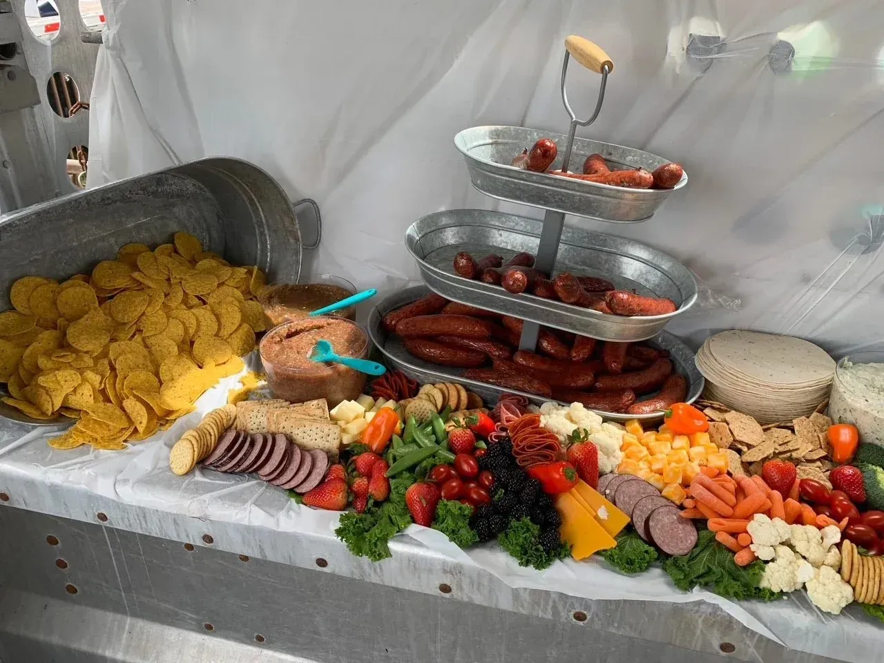 Assorted fruit, cheese, and pastries arranged buffet-style on a covered table with silver trays