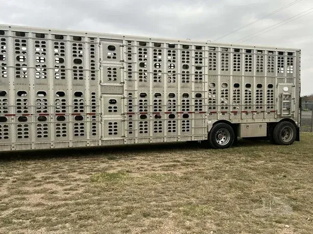 Large silver livestock trailer parked on grass under an overcast sky