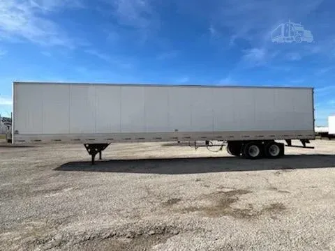 White semi-trailer truck parked on a gravel lot under a blue sky