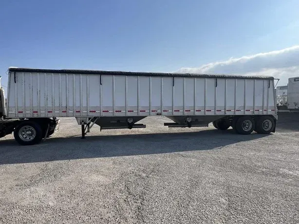 White semi-trailer truck parked on gravel under a blue sky