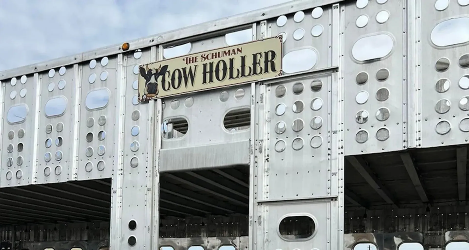 Weathered metal storefront with a sign reading “The Owl Holla” and many circular decorations