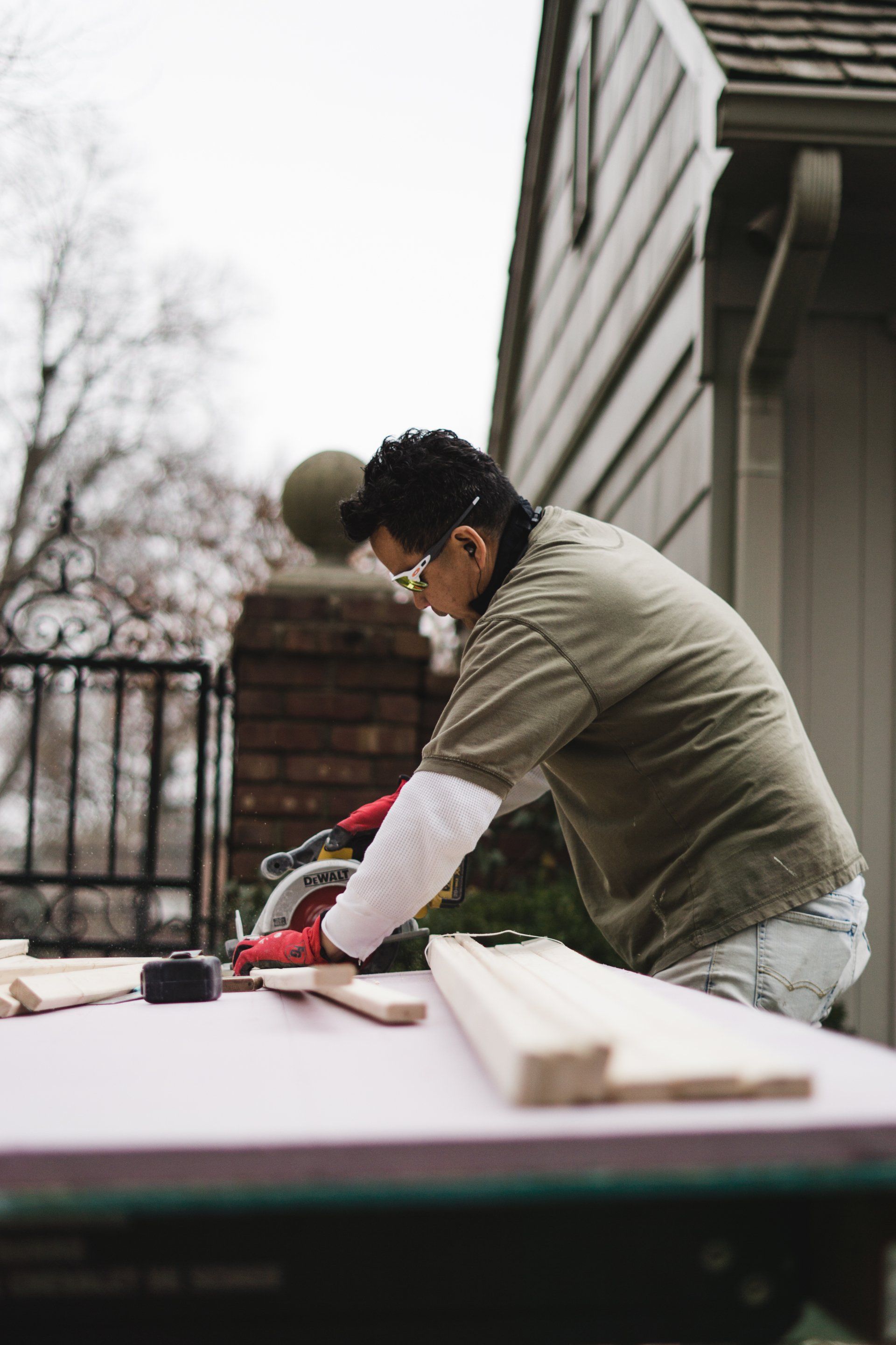 Person using a circular saw to cut wood on a work table outdoors.