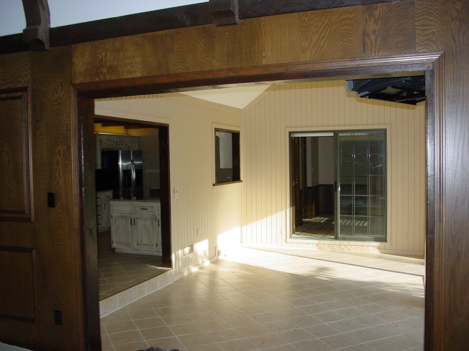Interior view of a room with a doorway and a sliding glass door. Beige walls, wood trim.