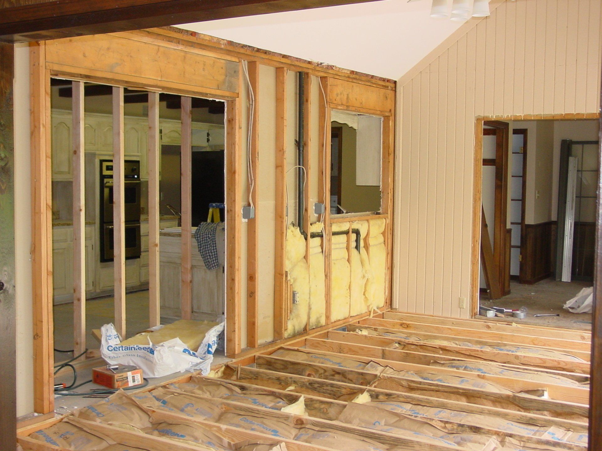 Interior construction: exposed framing, insulation, unfinished walls and floor, doorway to another room.