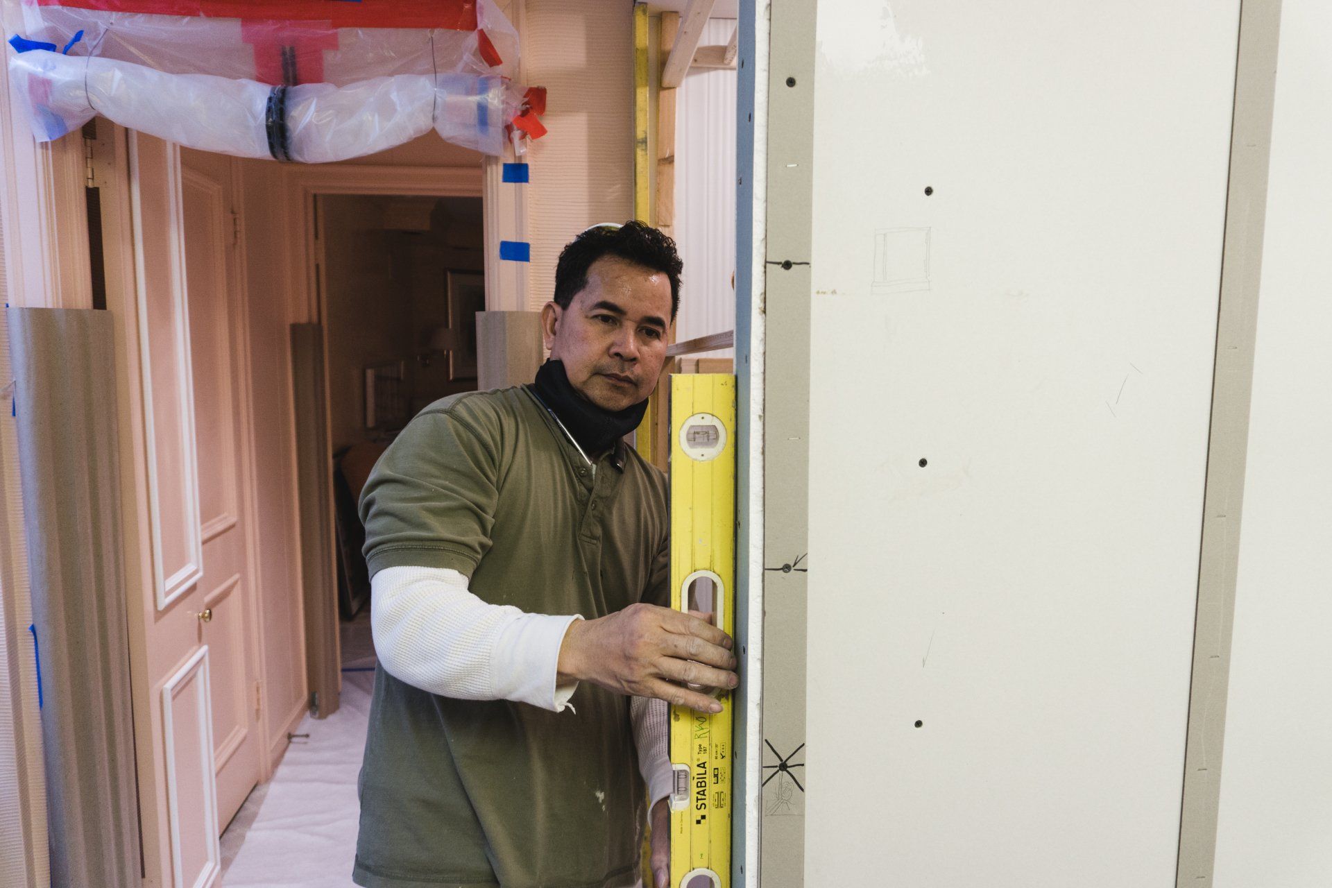Man using a level on drywall in a doorway, construction setting.