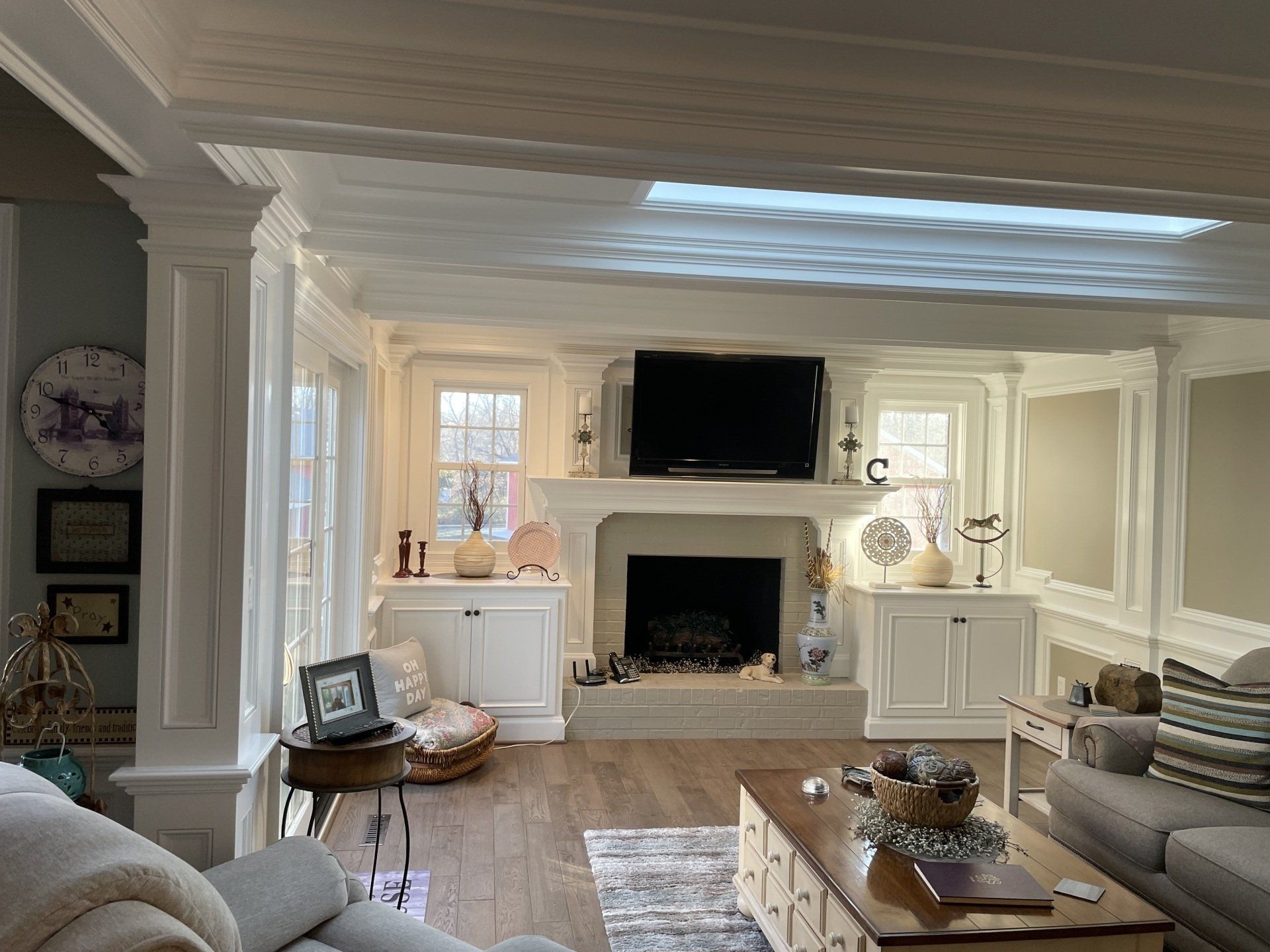 Living room with fireplace, white built-ins, and a mounted TV. A coffee table and sofa are in front.