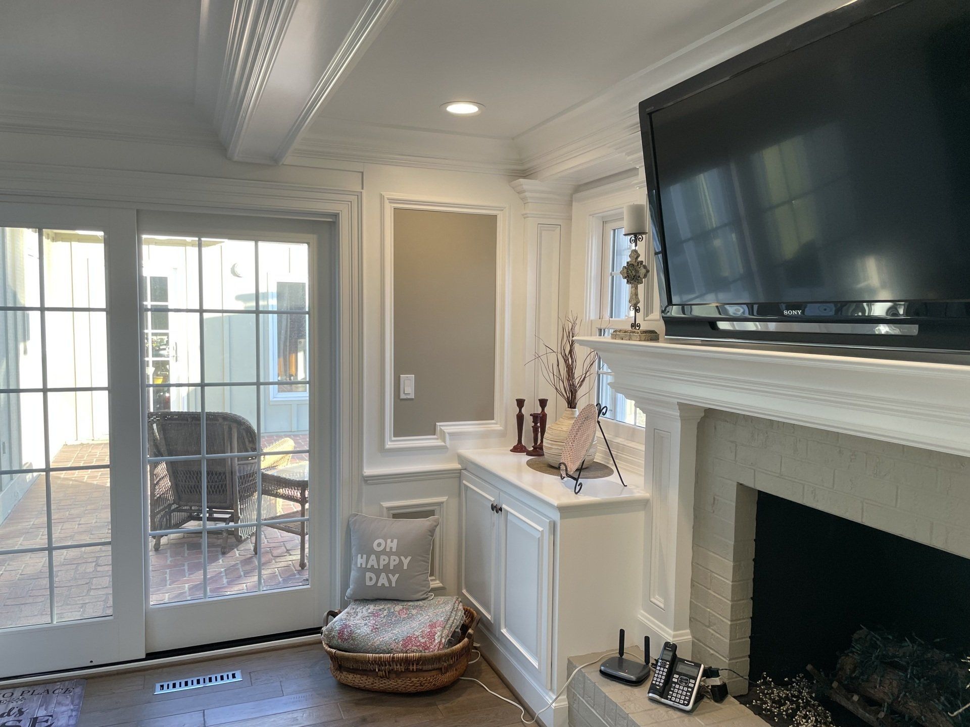 Living room with a fireplace, TV, and sliding glass door to a patio. White cabinetry and trim.