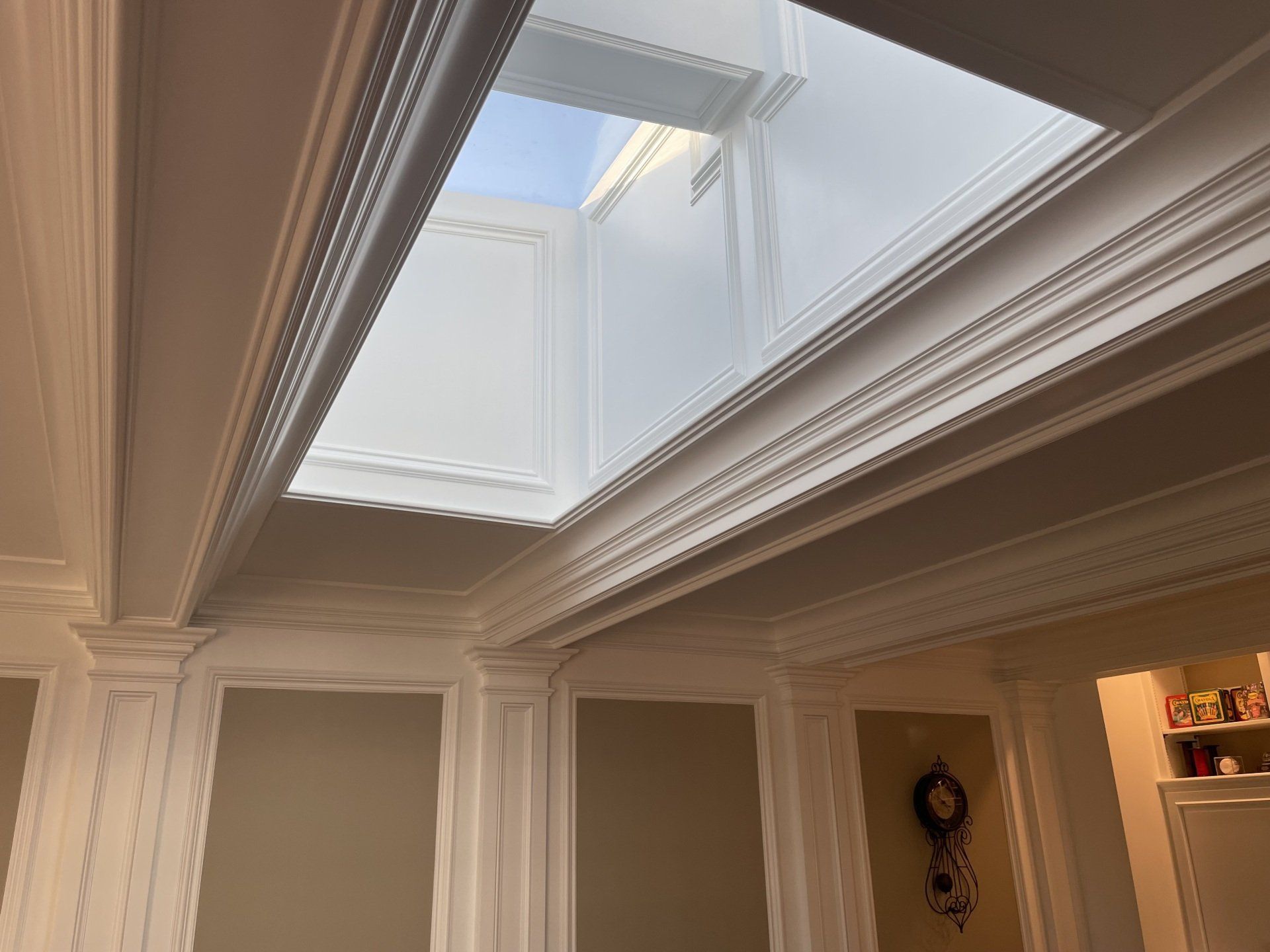Skylight in a white-walled room with decorative molding; sunlight streams in.
