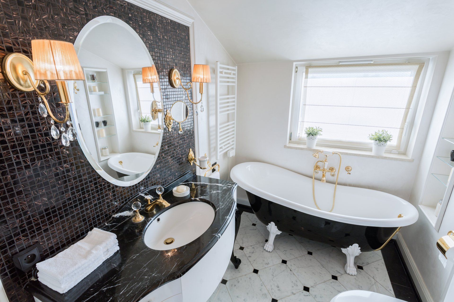 Elegant bathroom with black and white mosaic tile, a clawfoot tub, and gold accents.