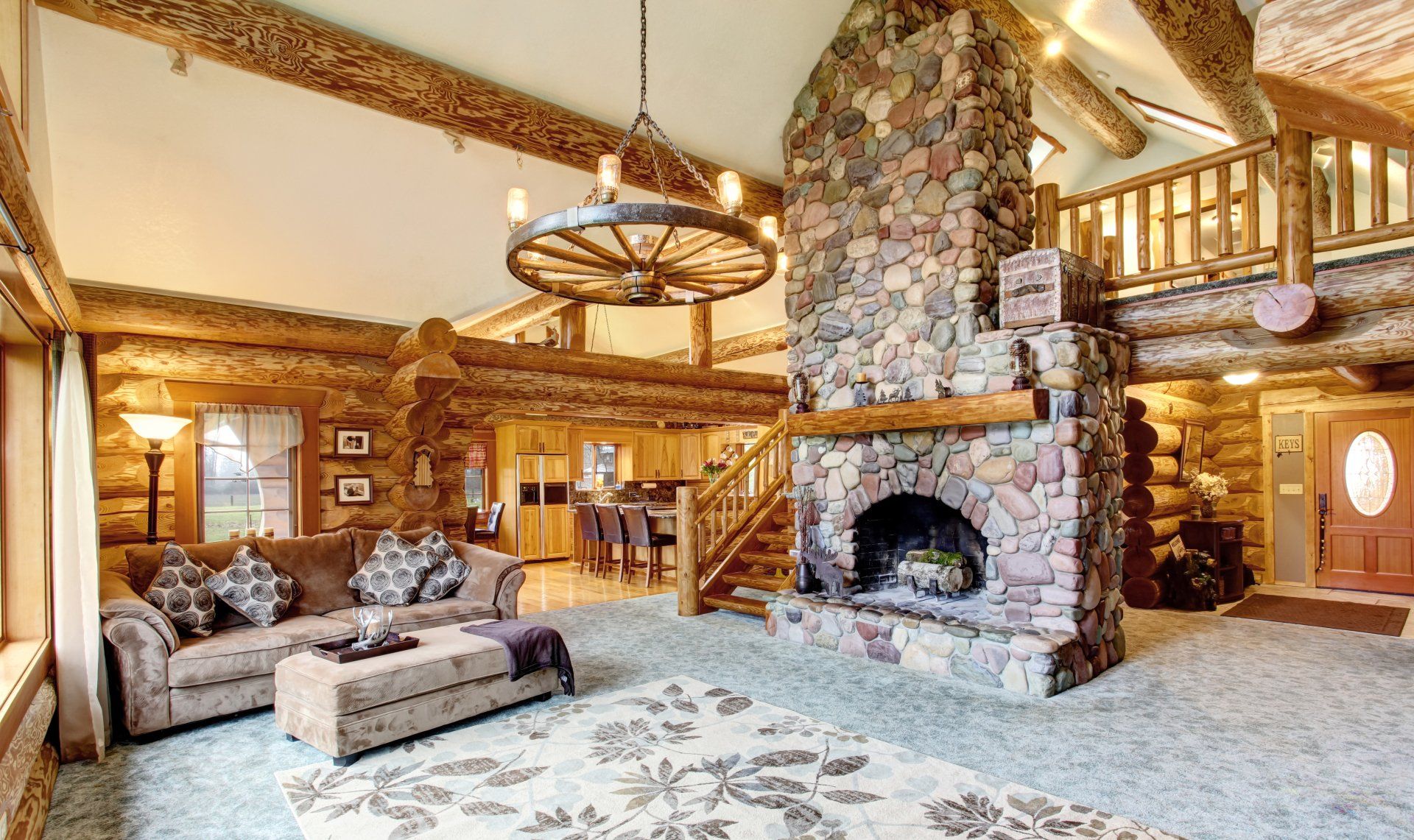 Rustic log cabin living room with stone fireplace, brown sofa, and wooden beams.