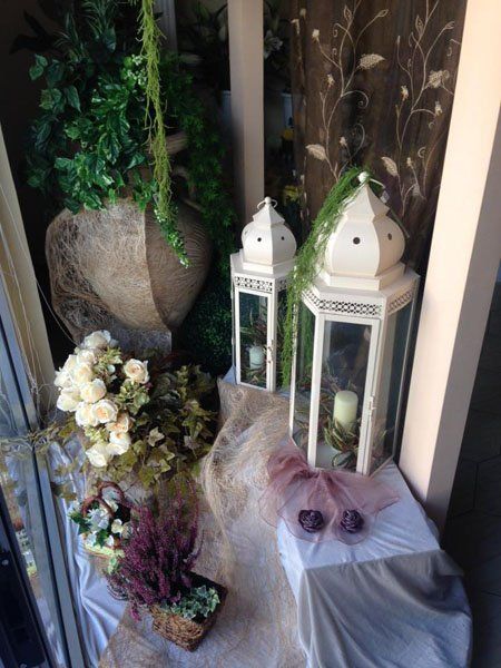 tavolo allestito con fiori e due lanterne con all'interno due candele