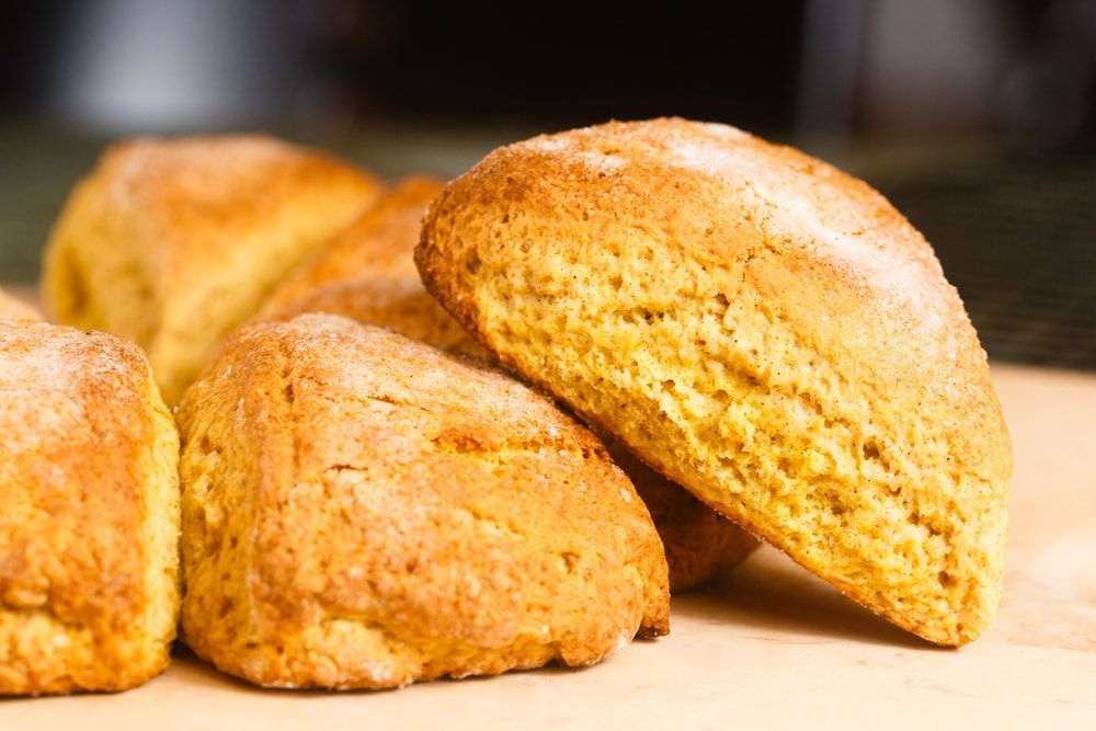 Golden-brown scones piled together, slightly textured, on a light-coloured surface. — Kape Centro In Childers, QLD