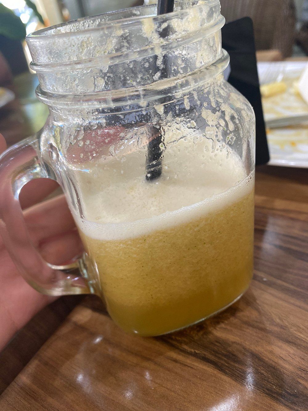 Glass Mug of Yellow-Brown Drink with Foam, Black Straw, on Wooden Table — Kape Centro In Childers, QLD