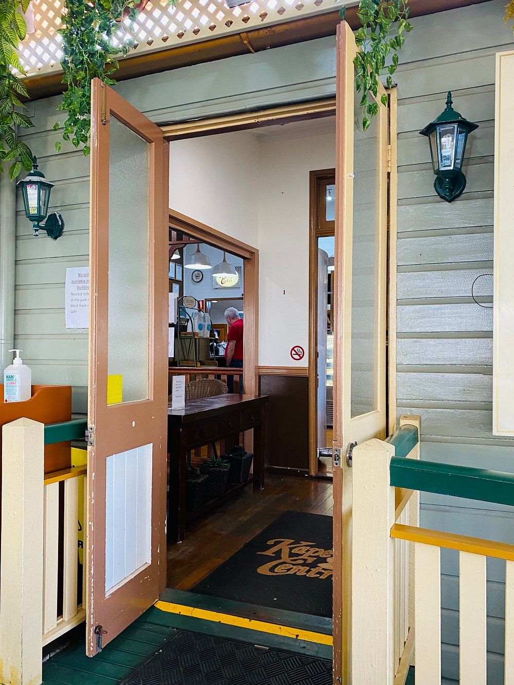 Outdoor Cafe with Wicker Chairs, Wooden Tables, and Hanging Plants — Kape Centro In Childers, QLD