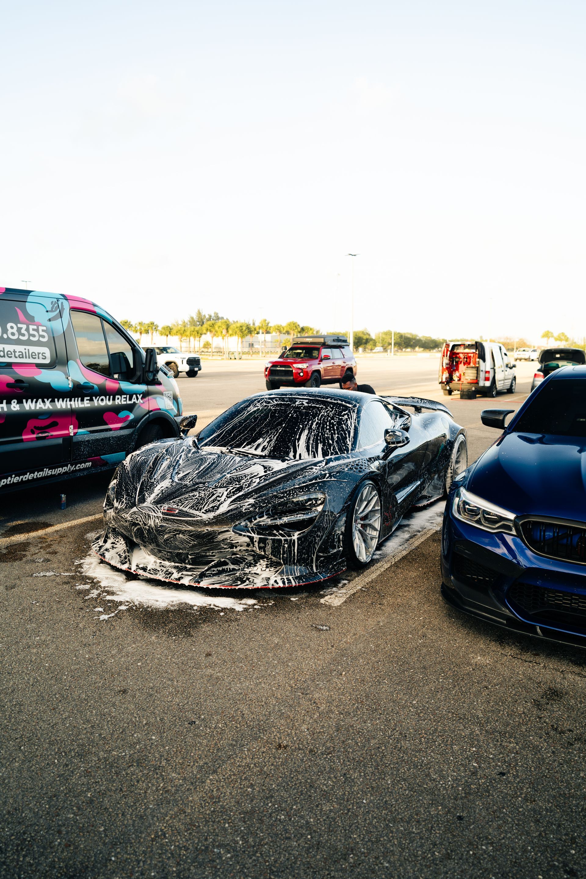A man is washing a blue car with a sponge.