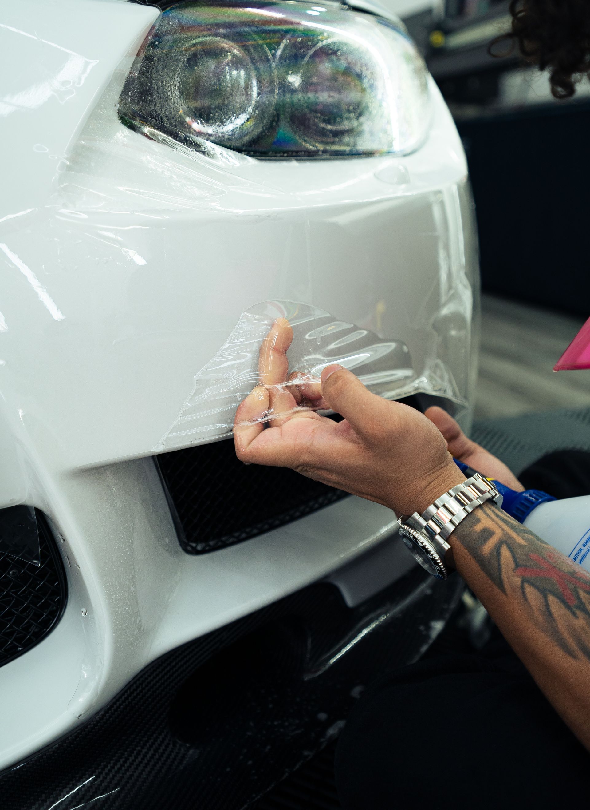 A person is applying a clear film to a black car