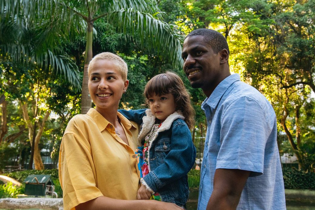 A man and woman are holding a child in a park.
