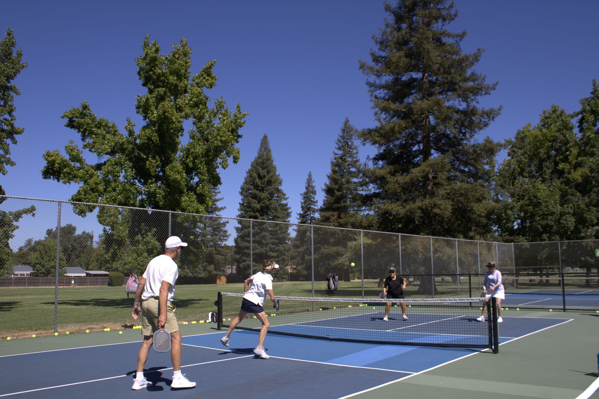 Two smiling boys with arms around each other in a park. One wears a track shirt, the other a striped shirt.