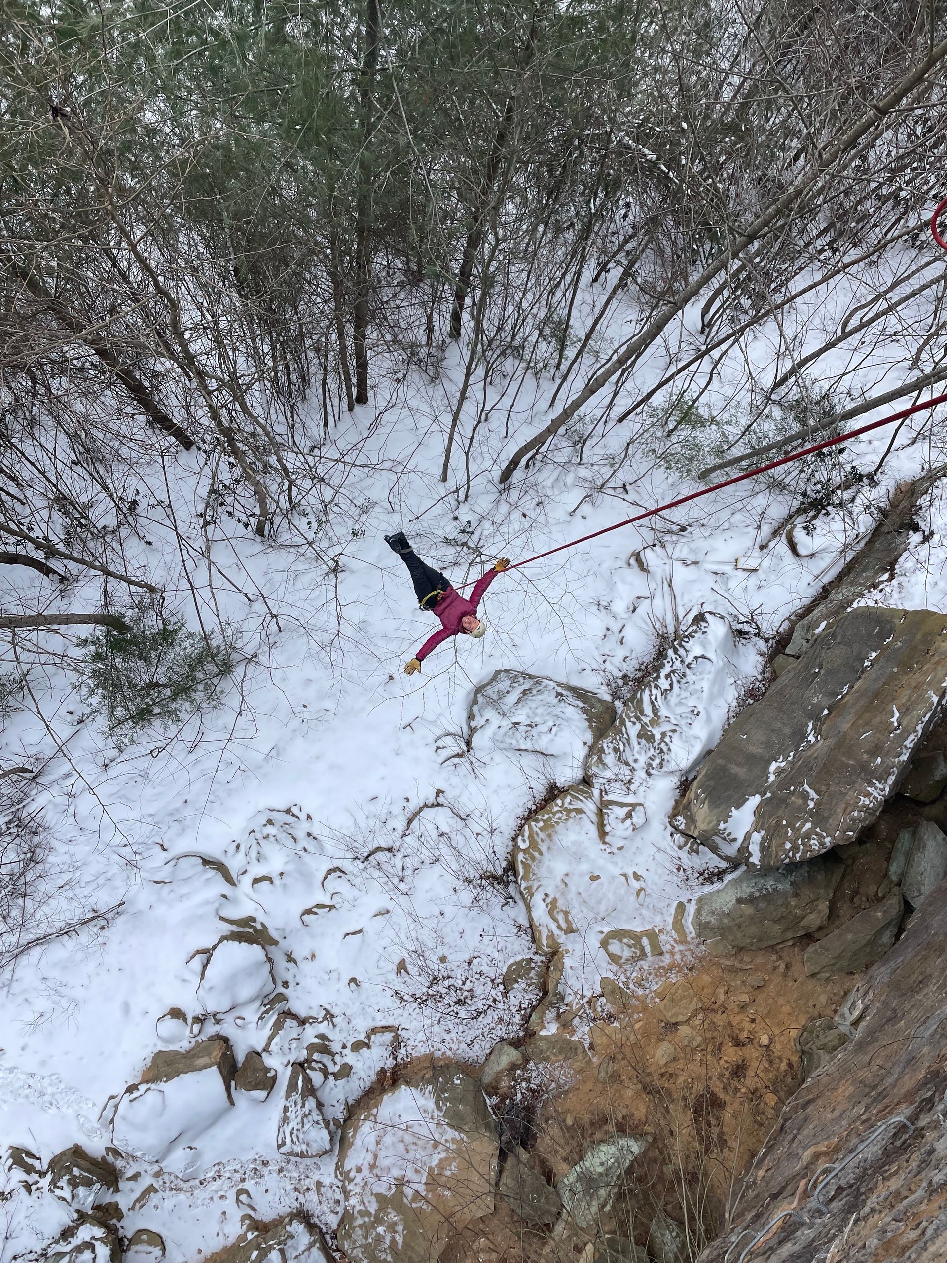 Winter climber on a hanging on a rope in the Red River Gorge, wearing cold-weather layers