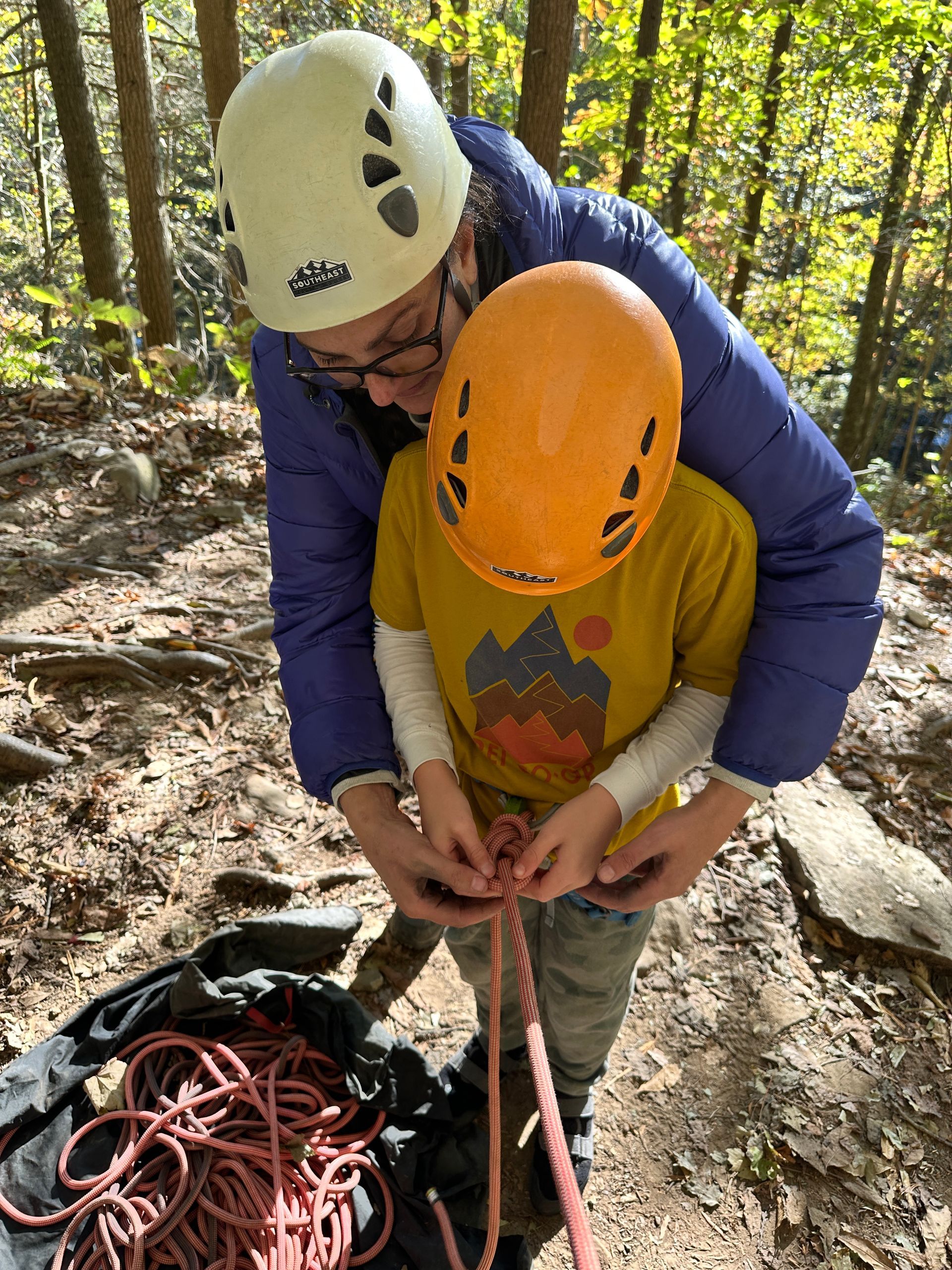 A mother helps her son tie a figure-8 knot after learning from their guide at Southeast Mountain Guides.