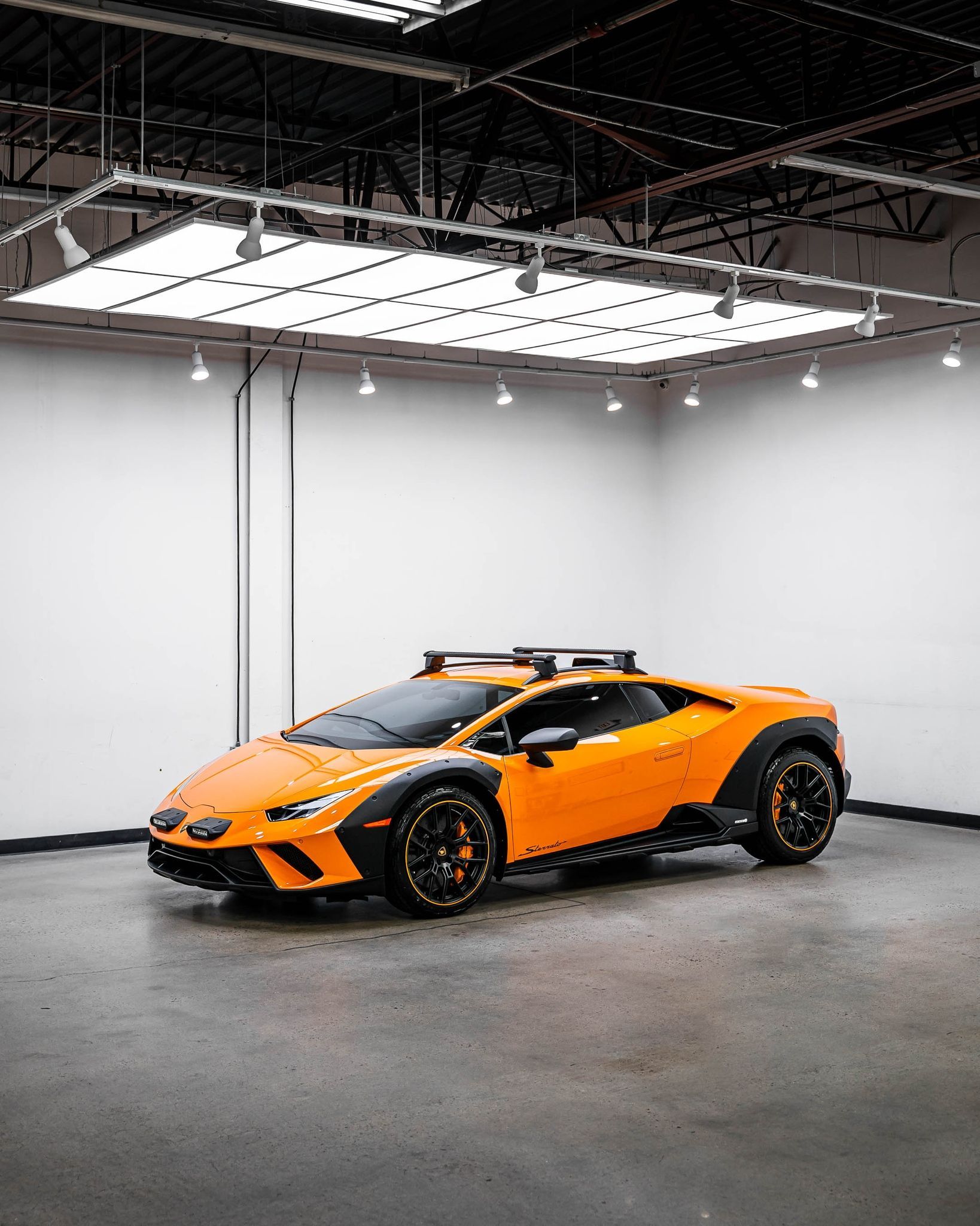 An orange lamborghini huracan is parked in a garage.