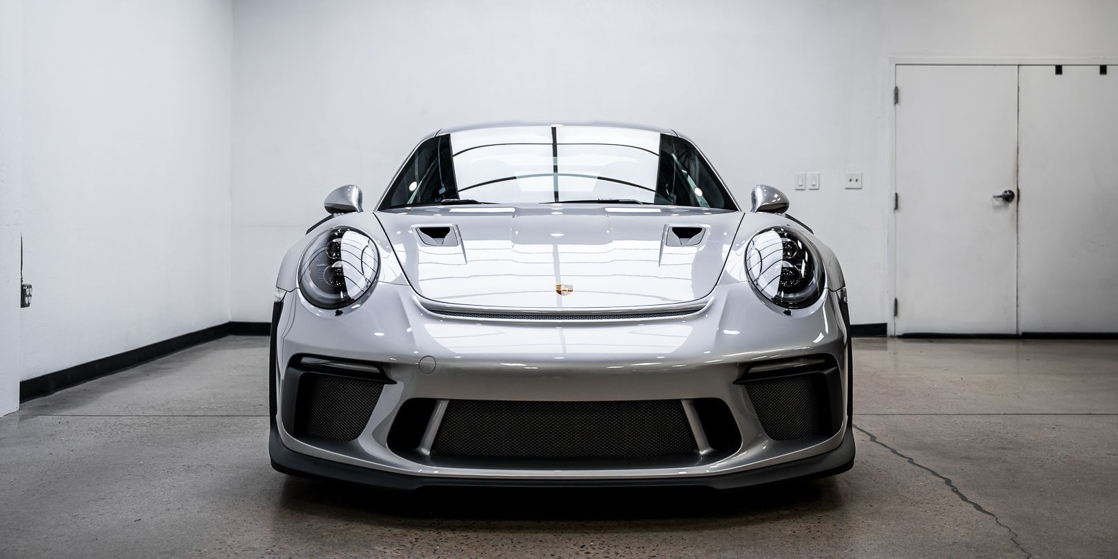 A silver porsche 911 gt3 rs is parked in a garage.