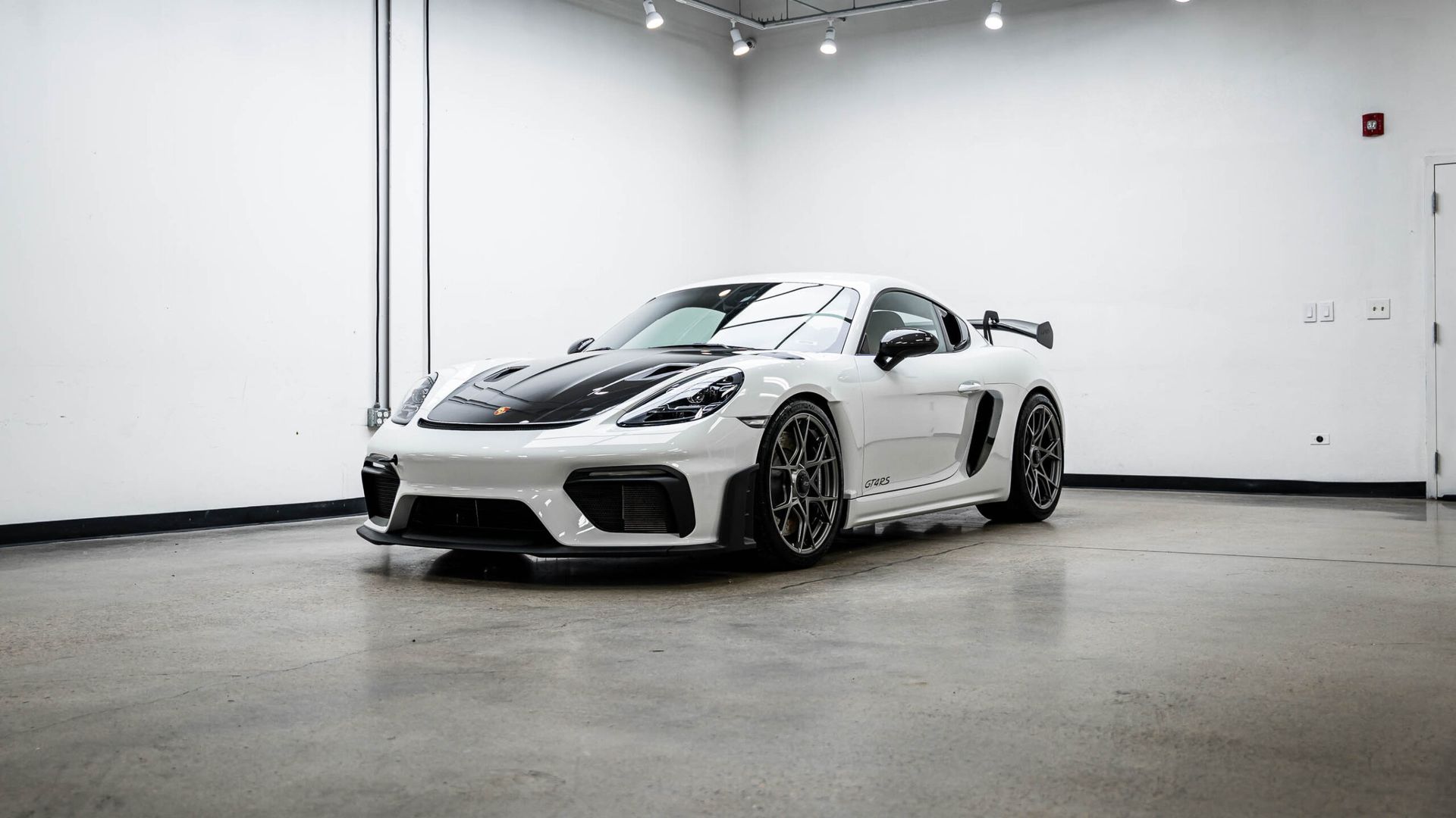 A white sports car is parked in a garage.